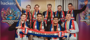 A group photo of the Dutch team celebrating at a HackerOne live-hacking event, holding a red, white and blue scarf. Co-founder of Skuridat, Mateus, bottom row, second from the left