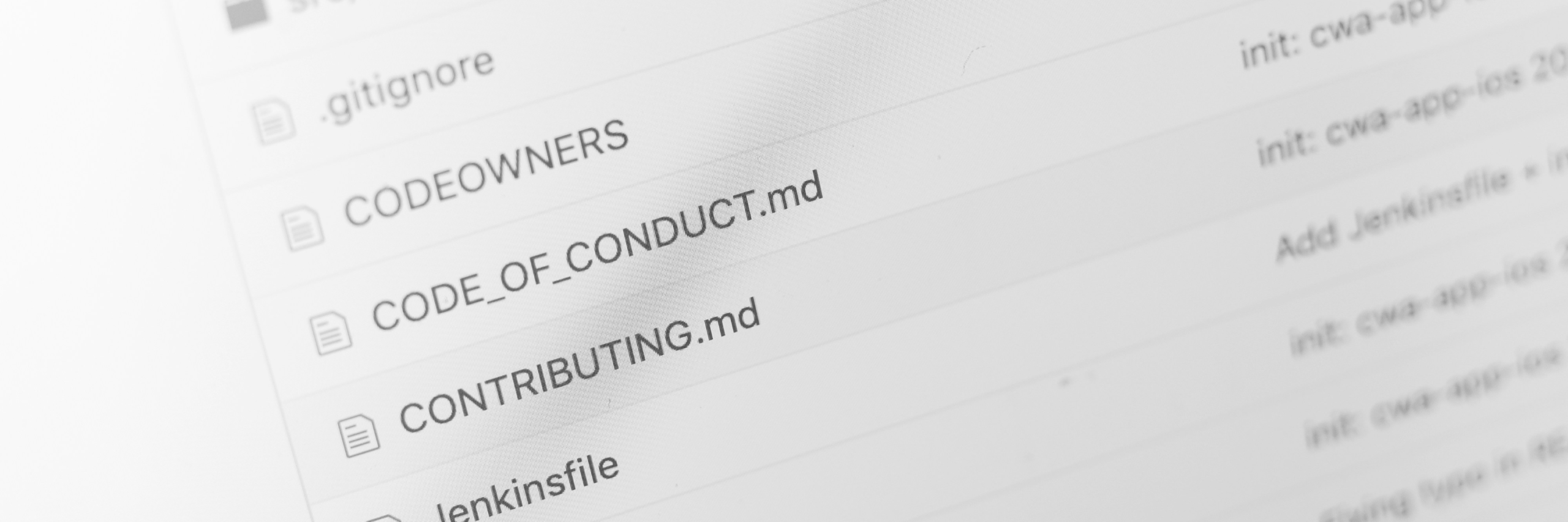Close-up of a code repository's file list with commit history visible in the background
